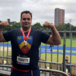 Todd Hodgetts flexes muscles after winning medal